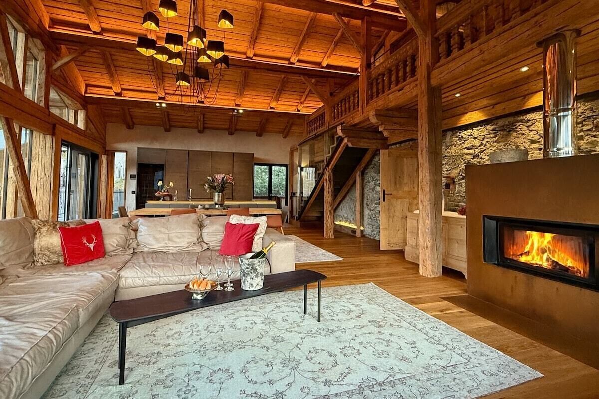 A spacious living area with a fireplace, wooden beams, and a cozy seating arrangement.
