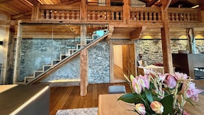 Ein Holzinnenraum mit Treppe, Steinwand und Blumen in einer Vase.