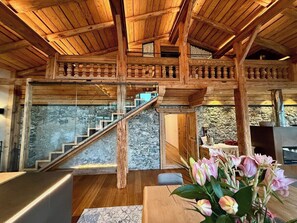 Un intérieur en bois avec un escalier, un mur en pierre et un vase de fleurs.