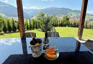 Et bord med en champagneflaske, et glas og en tallerken med mad, med en smuk bjergudsigt i baggrunden.