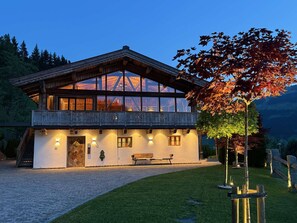 A chalet-style building with a balcony, wooden exterior, and a stone pathway leading to the entrance.