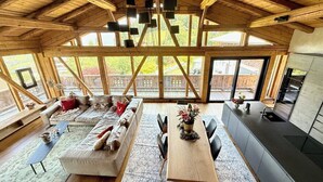 Eine geräumige Küche mit einer großen Kochinsel, ein Essbereich mit Holztisch und Stühlen sowie eine gemütliche Sitzecke mit Sofa und Kissen.