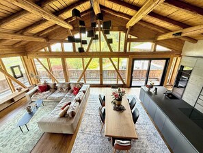 Une cuisine spacieuse avec un grand îlot central, un coin repas avec une table et des chaises en bois, et un coin salon confortable avec un canapé et des coussins.