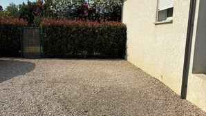 A gravel driveway leading to a building with a window and a door.