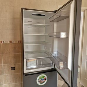 An empty refrigerator with a sticker on the door.