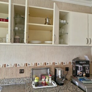 Uma cozinha com armários, uma máquina de café e um balcão com diversos objetos.
