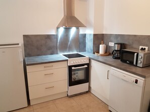 A compact kitchen with a stove, oven, microwave, and coffee maker.