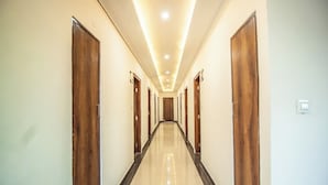 A long, well-lit hallway with wooden doors and a tiled floor. - Manali Heaven (Manali)