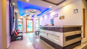 A reception area with a modern design, featuring a reception desk, seating area, and a glass door leading to the outside. - Manali Heaven (Manali)