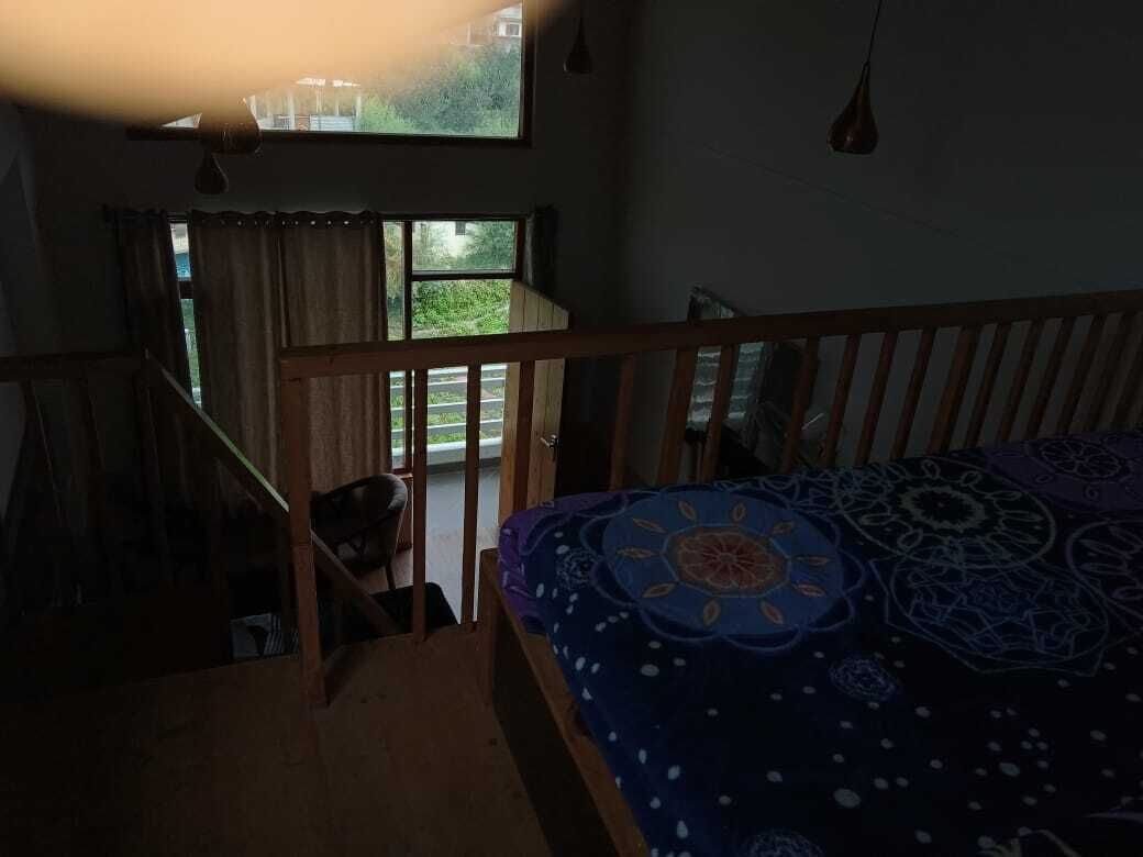 A bedroom with a bed, a window, and a staircase.