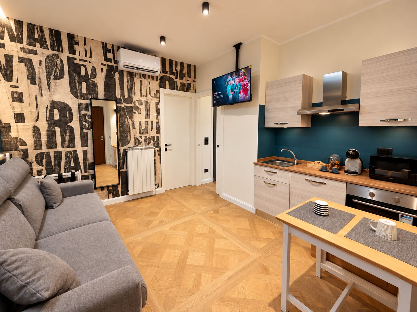 A modern kitchen with a flat-screen TV, wooden cabinets, and a dining area with a table and chairs.