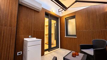 Un baño moderno con un lavabo blanco, paneles de madera y una puerta de cristal que da a la zona de la ducha.