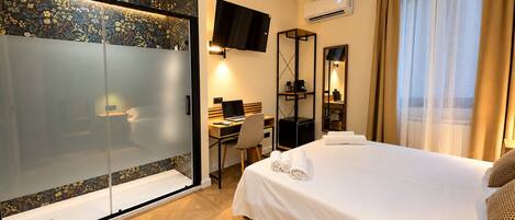 Ein Hotelzimmer mit Bett, Schreibtisch und Fernseher.