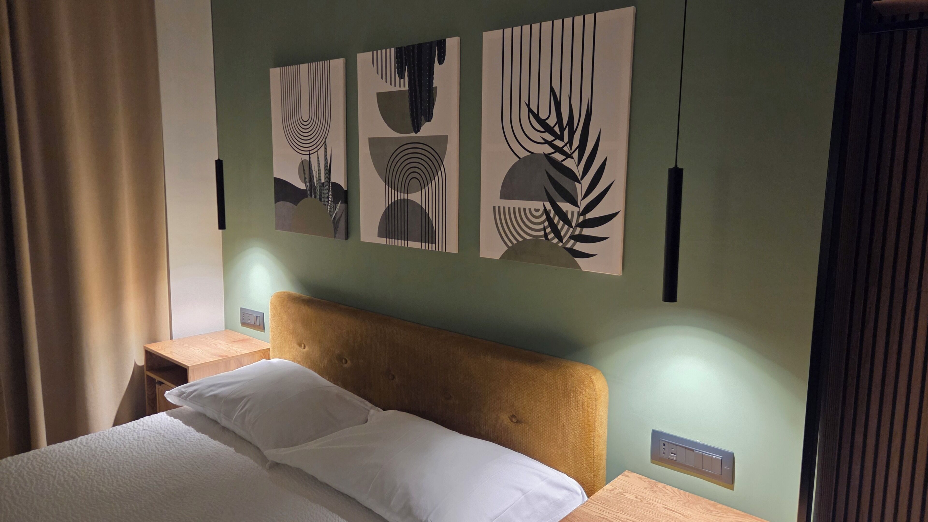 A hotel room with a bed, a headboard, bedside tables, and wall art.