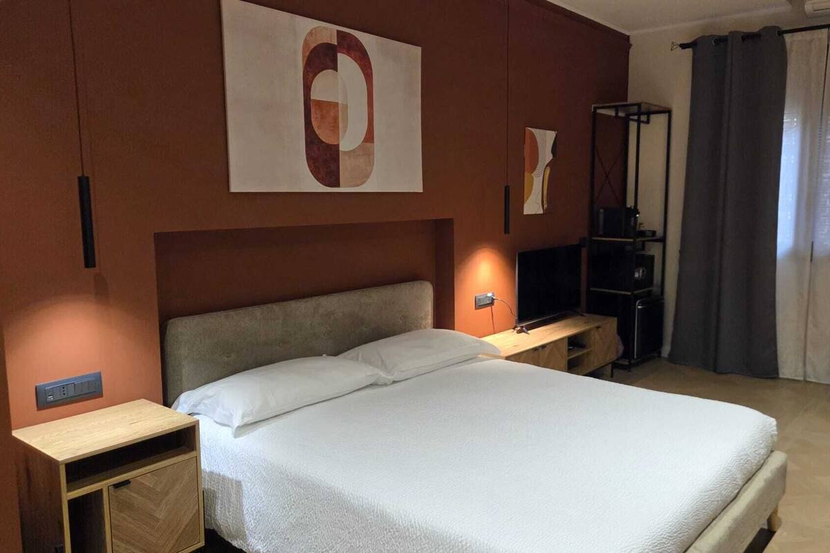 A hotel room with a bed, a desk, a television, and a wardrobe.
