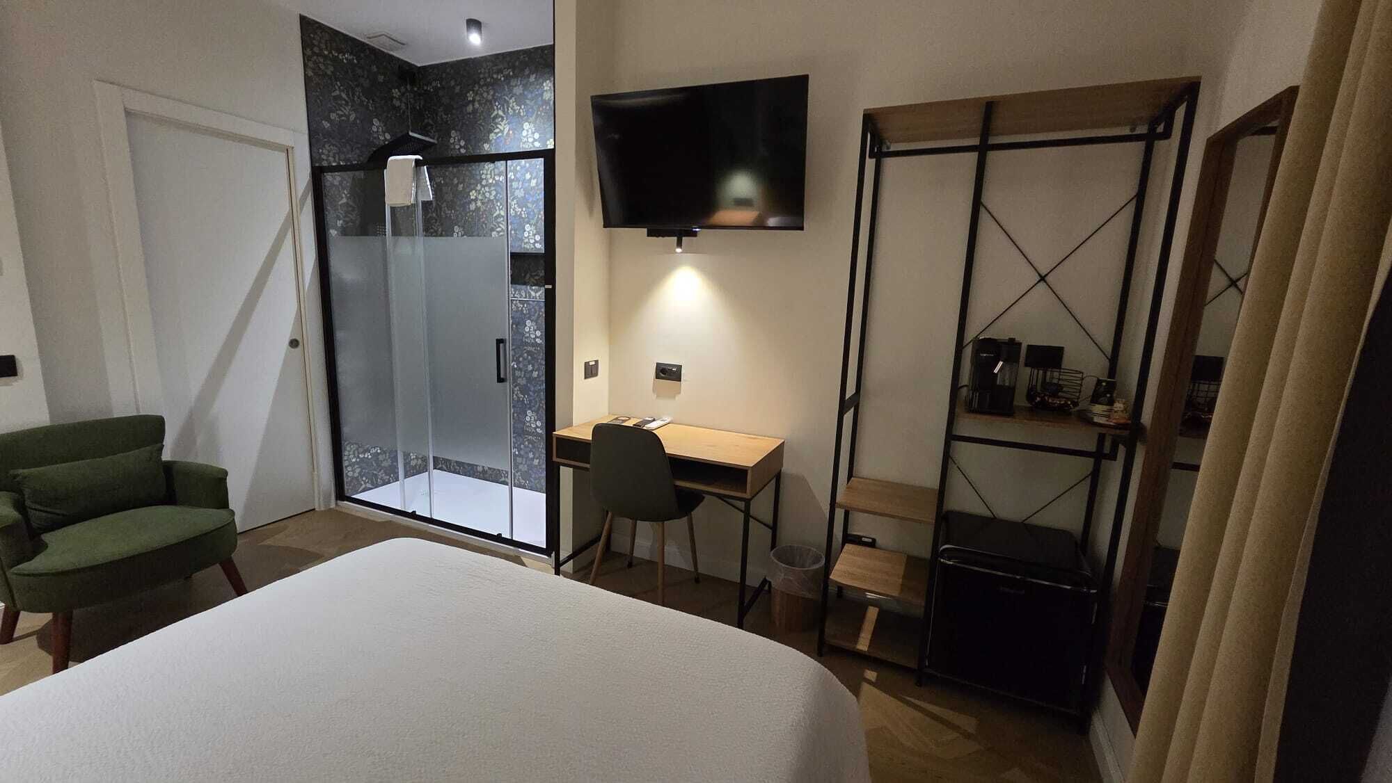 Ein Hotelzimmer mit Bett, Schreibtisch, Stuhl, Fernseher, Dusche und Kleiderschrank.