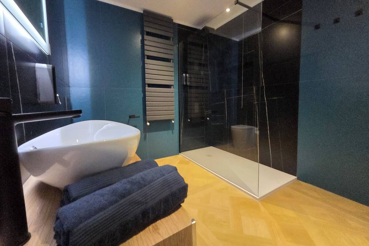 A modern bathroom with a large white sink, a glass shower enclosure, and a wooden vanity.