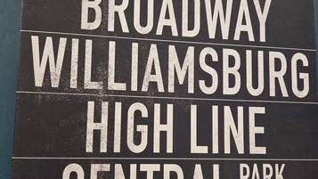 Un panneau indiquant les lieux suivants : « Upper East Side, Broadway, Williamsburg, High Line, Central Park, Midtown ».