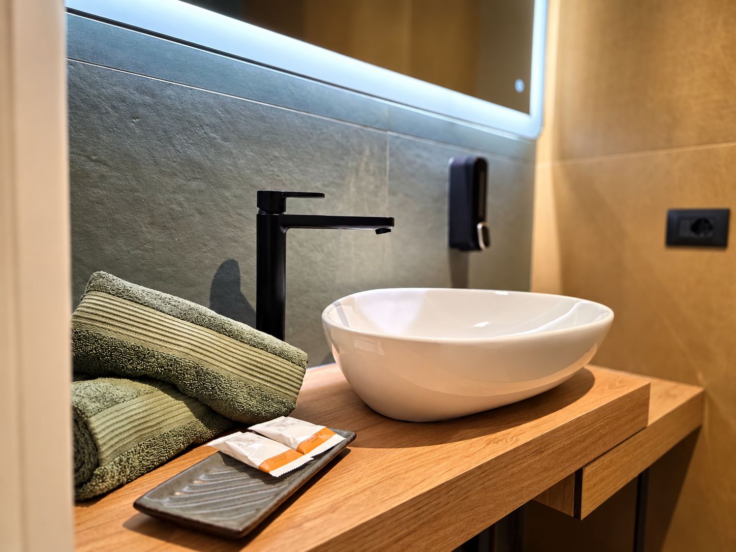 A modern bathroom with a white basin, a black faucet, and a towel on the counter.