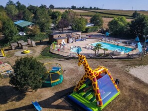 A fenced outdoor area with a pool, inflatable play structures, and a slide. - Cozy chalet for 5 people with terrace, pond view (Naucelle)