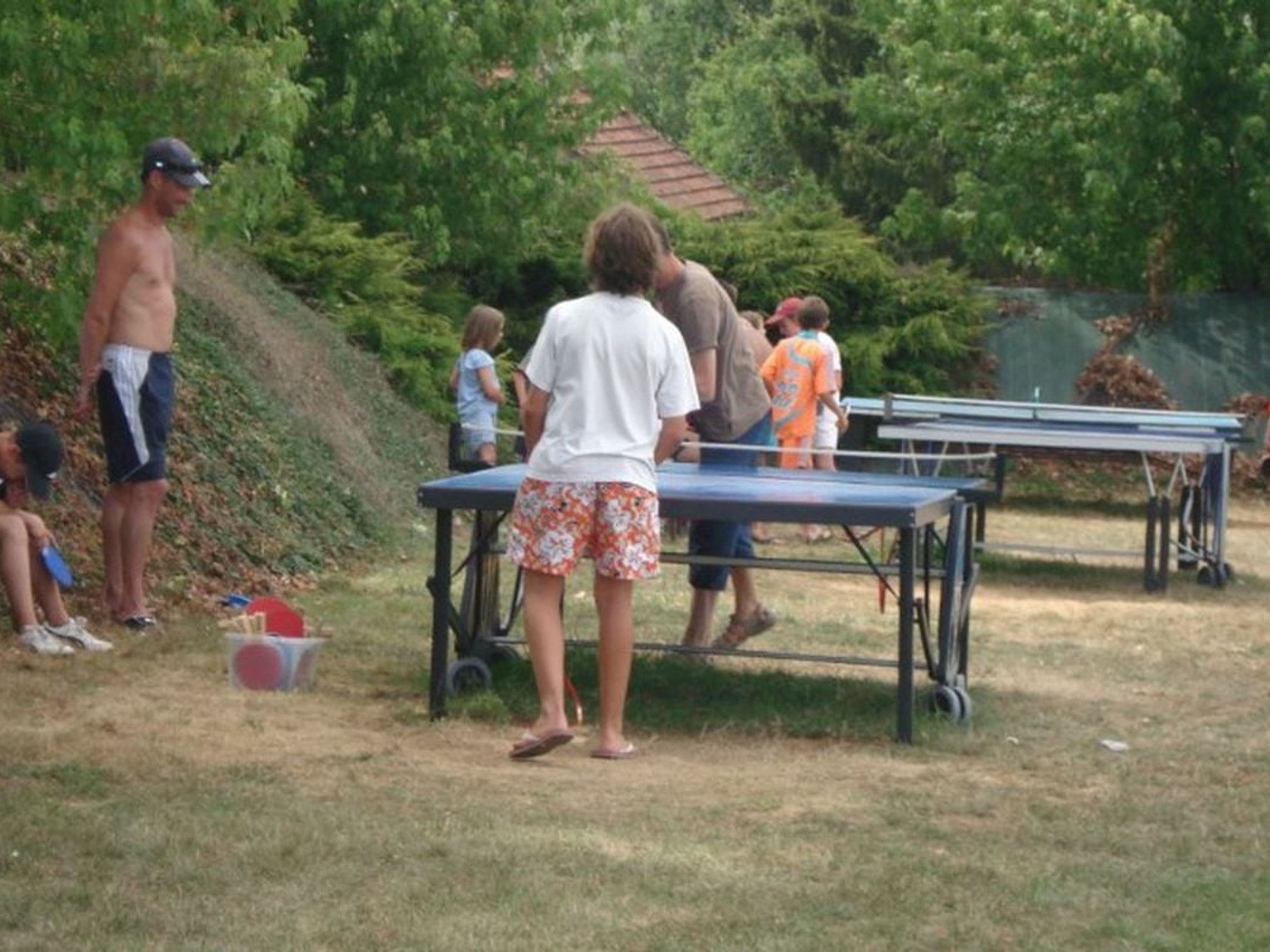 Ein Außenbereich mit einem Tischtennis-Tisch und einer Person in der Nähe.