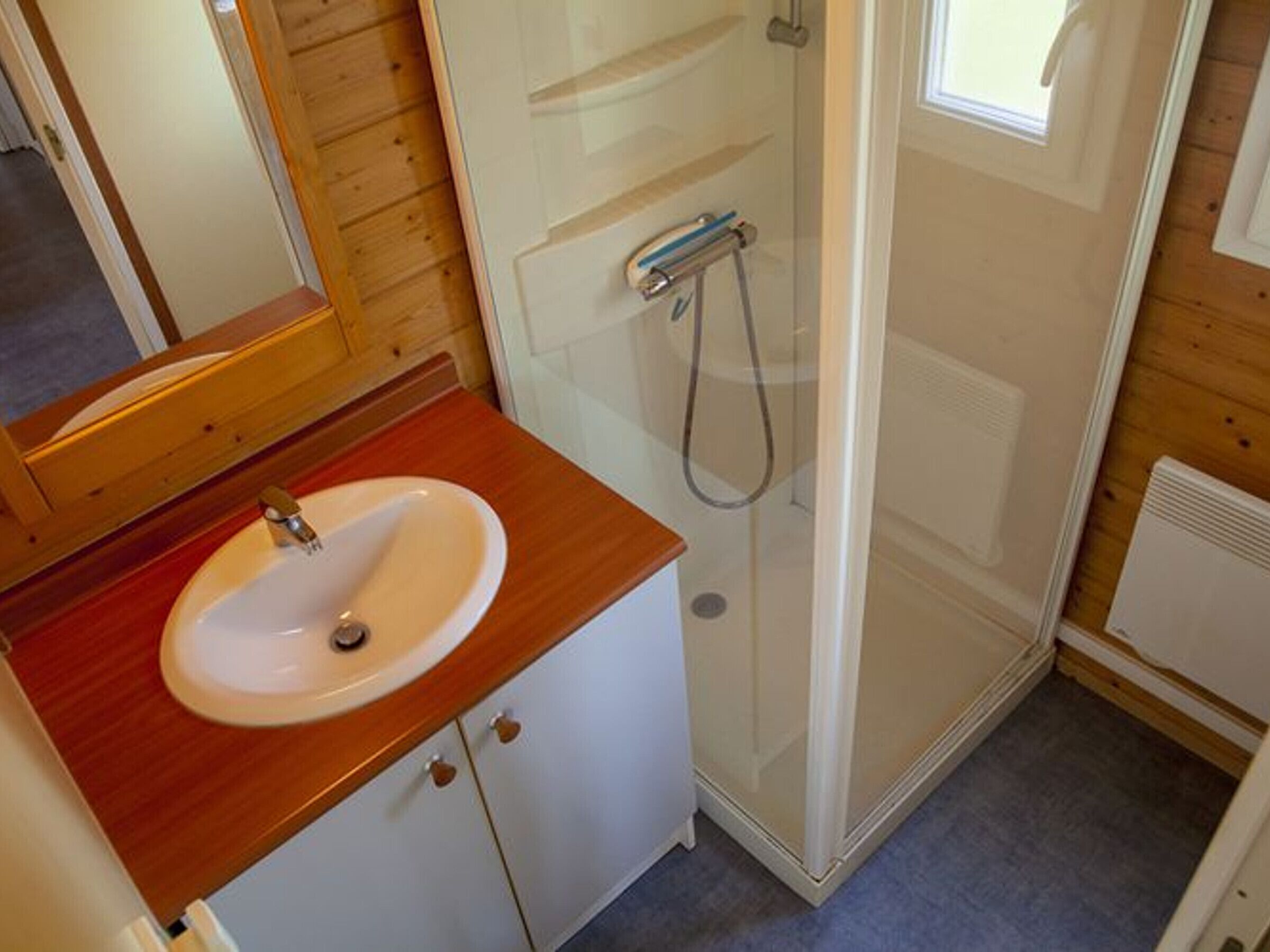 Un bagno con un mobile bagno in legno, un lavandino e un box doccia in vetro.