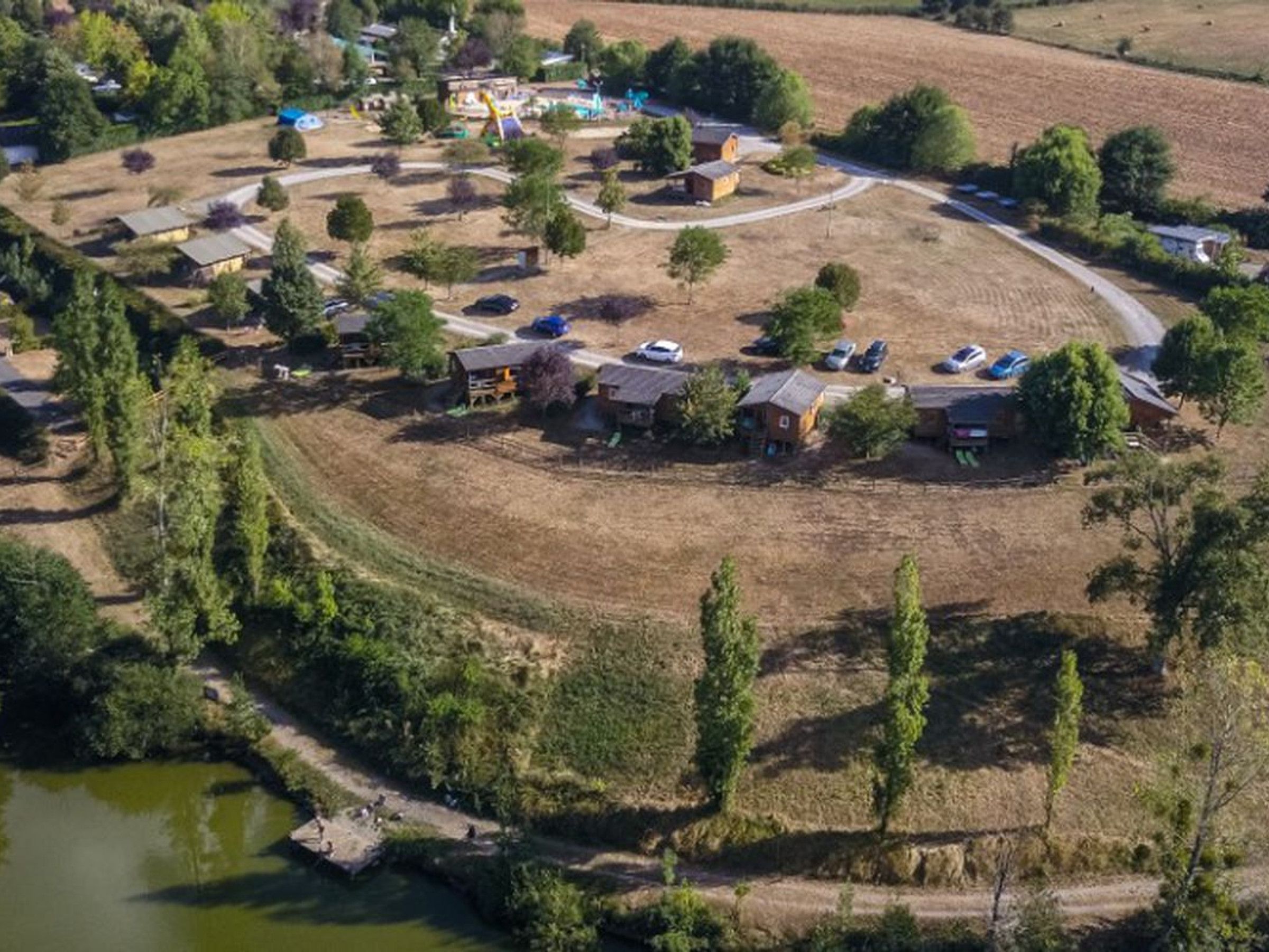 An aerial view of a residential area with houses, a playground, and a small body of water.
