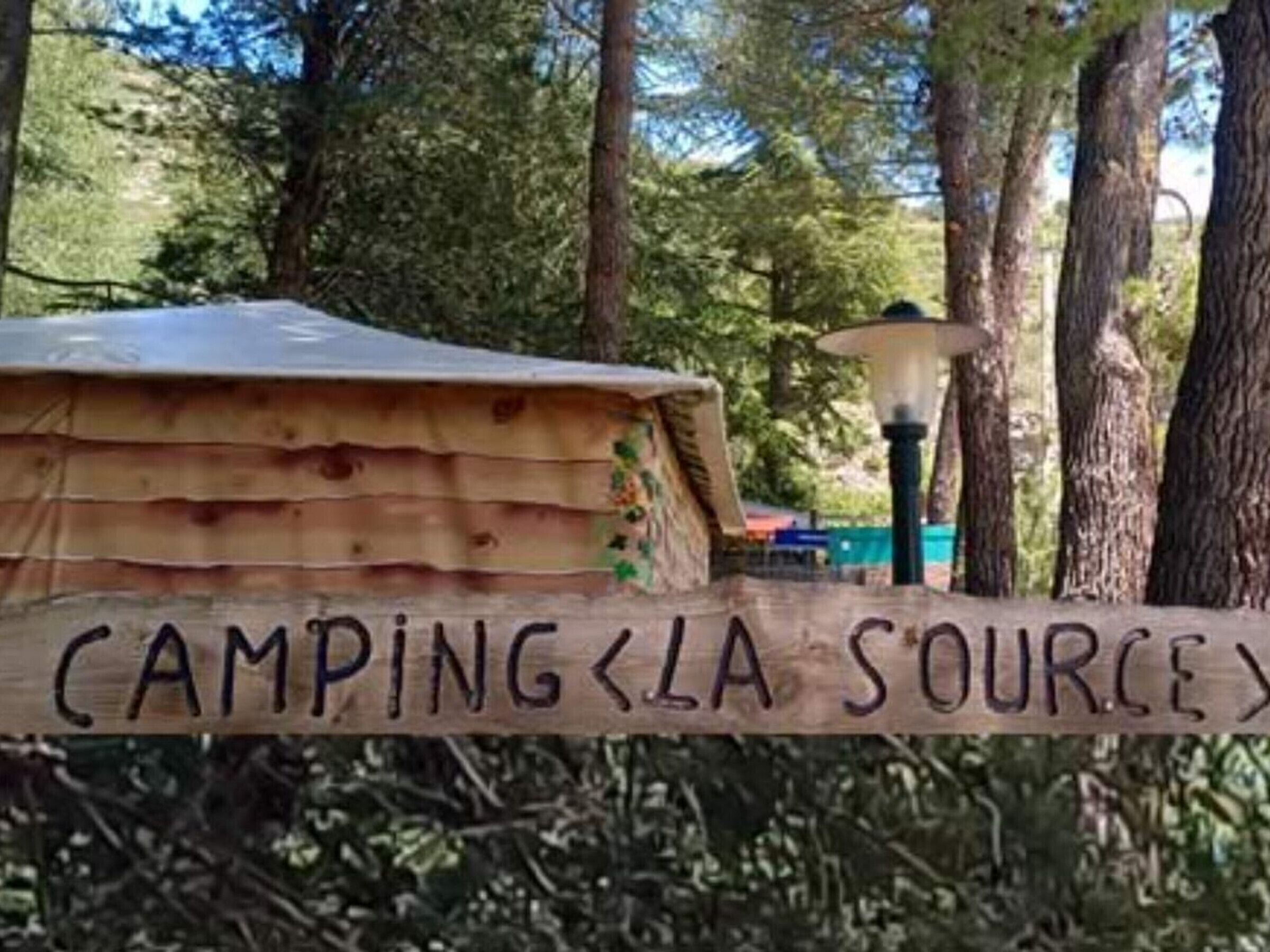 Une structure en bois sur laquelle est apposée une enseigne indiquant « CAMPING LA SOURCE ».