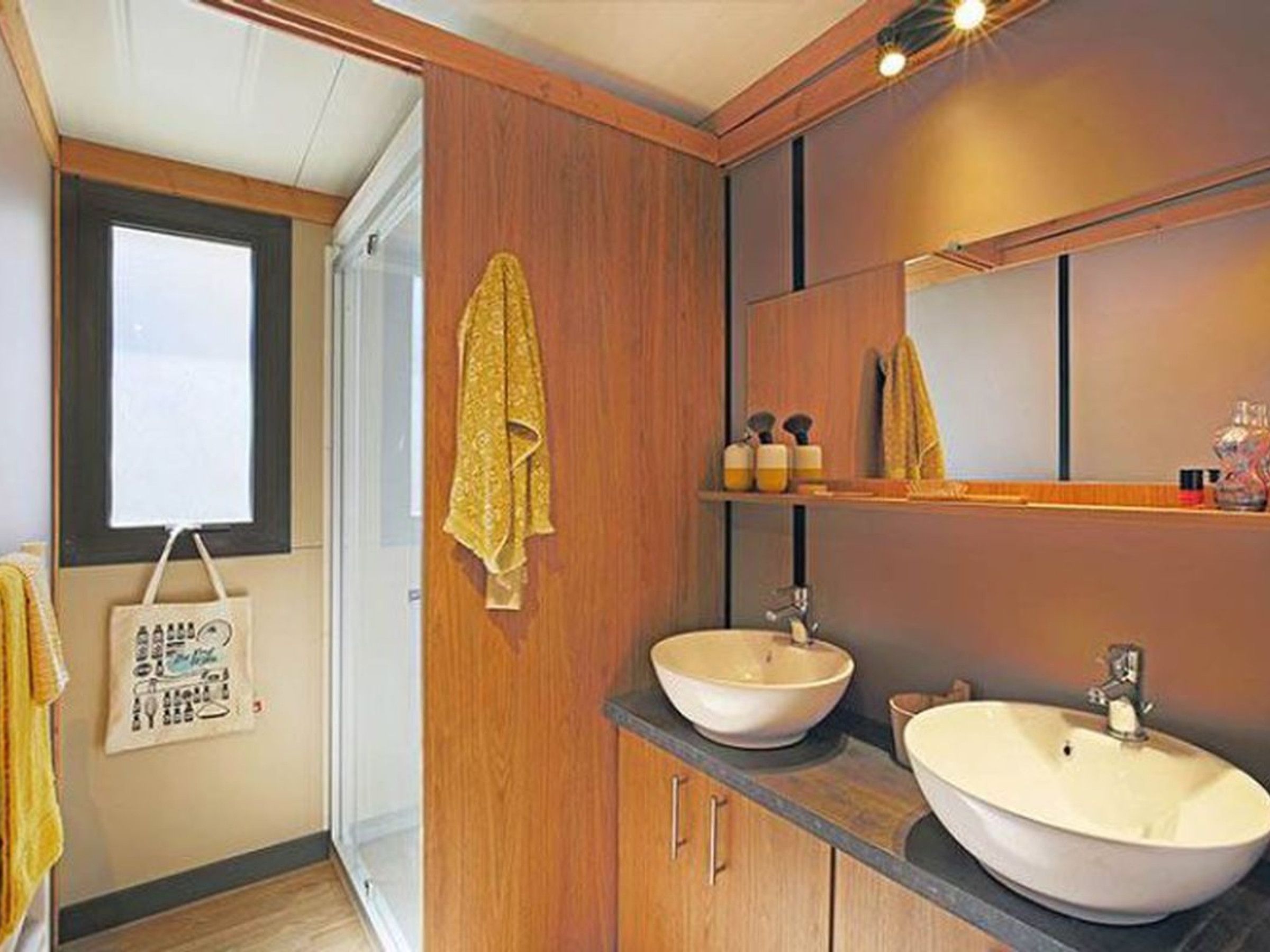 A bathroom with wooden cabinetry, two sinks, a mirror, and a towel hanging on the wall.