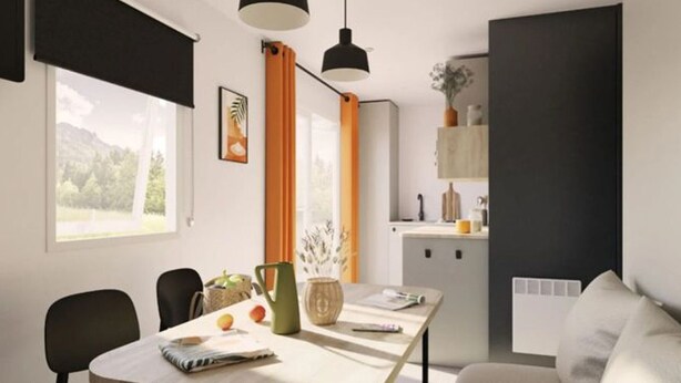 A modern living room with a dining area, featuring a sofa, a table with fruits and a kettle, and a view of the outdoors.