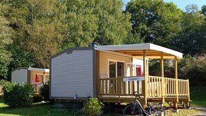 A mobile home with a covered porch and a bicycle parked outside.