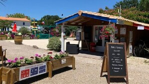 Un petit café en plein air avec un banc en bois et une enseigne publicitaire indiquant les plats et les boissons proposés.