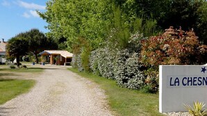Un chemin de gravier mène à un bâtiment sur lequel est apposée une enseigne indiquant « LA CHESN ».