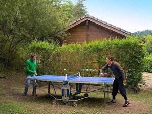Two people playing table tennis outdoors with a portable table.