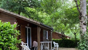 Eine Holzhütte mit Veranda, weißen Plastikstühlen und Kiesgrund.
