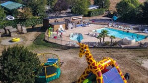 A playground with a giraffe-shaped slide and a pool area with lounge chairs and umbrellas. - Spacious chalet for 8 people - Pond view - Terrace (Naucelle)