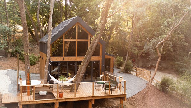 Une cabane en bois dotée d’une terrasse, d’un hamac et d’un foyer extérieur.