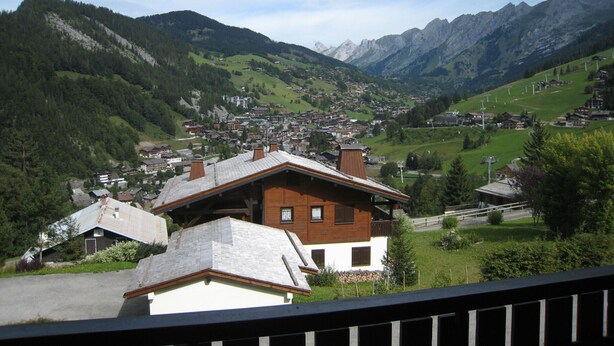 Ein Bergdorf mit traditionellen Häusern, blauem Himmel und Blick auf die umliegenden Hügel.