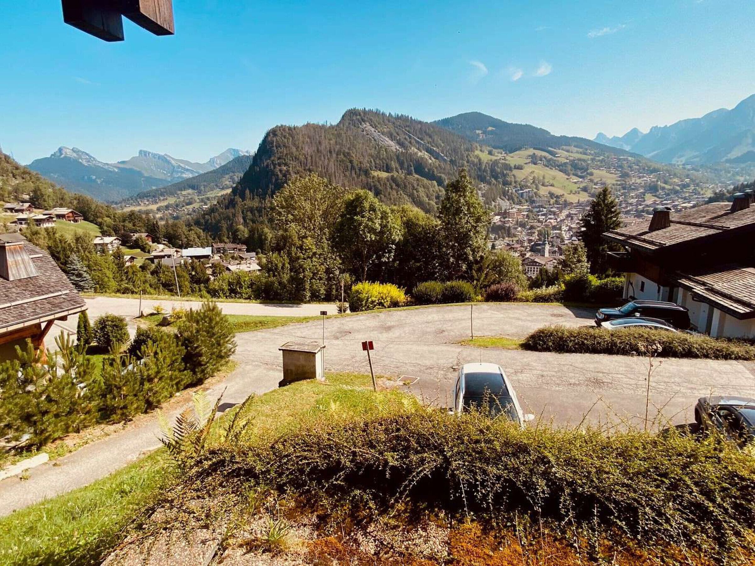 A residential area with houses, a parking lot, and a mountainous backdrop.