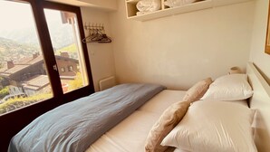 Ein Schlafzimmer mit Bett, Kissen, einem Fenster und Blick auf Gebäude.