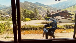 Blick vom Balkon mit einem Stuhl auf eine Stadt und Berge.