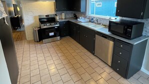 A modern kitchen with black cabinets, stainless steel appliances, and a tiled floor.