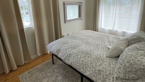A bedroom with a bed, a small window, and a view of the outside.