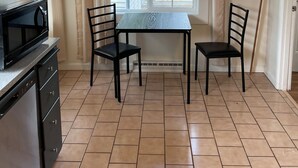A kitchen with a dining table and chairs, a microwave, and a window with curtains.