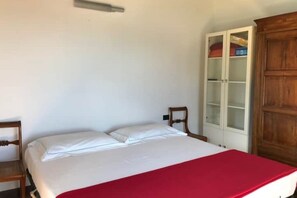 A single bed with a red blanket, a wooden chair, and a white wardrobe with glass doors. - Mergozzo Beach Villa Panorama (Mergozzo)