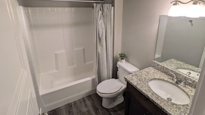 A bathroom with a shower, toilet, sink, and vanity. - Modern 1BR by Silicon Slopes – Workspace & 65” TV (American Fork)