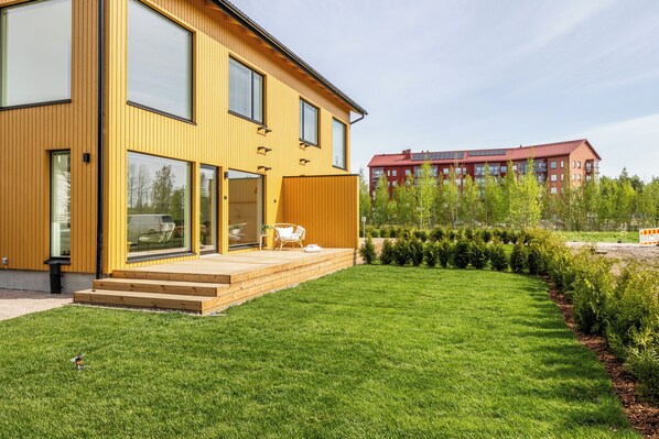 A modern yellow building with large windows and a wooden deck.