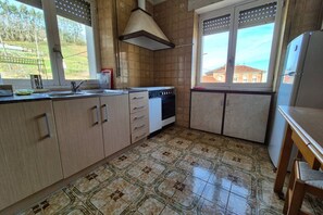 A kitchen with a stove, sink, cabinets, and a window with a view. - 14A05 Apartment with a View by R2R Consulting (Lastres)