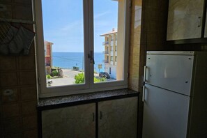 A kitchen with a view of the sea, a refrigerator, and cabinets. - 14A05 Apartment with a View by R2R Consulting (Lastres)