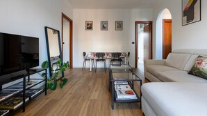 Una sala de estar con televisor, sofá, mesa de centro y un comedor con sillas y una mesa.